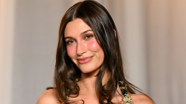 Hailey Bieber smiles in a beaded dress and dark brunette waves.