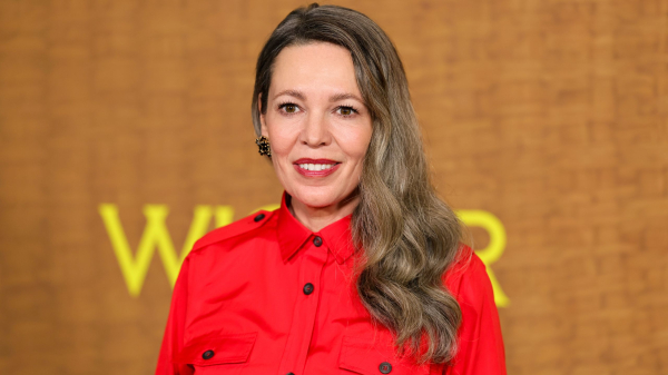 Olivia Colman smiling and wearing a red shirt